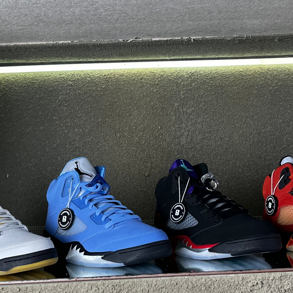 Four pairs of sneakers in a concrete box with a light shining on them.